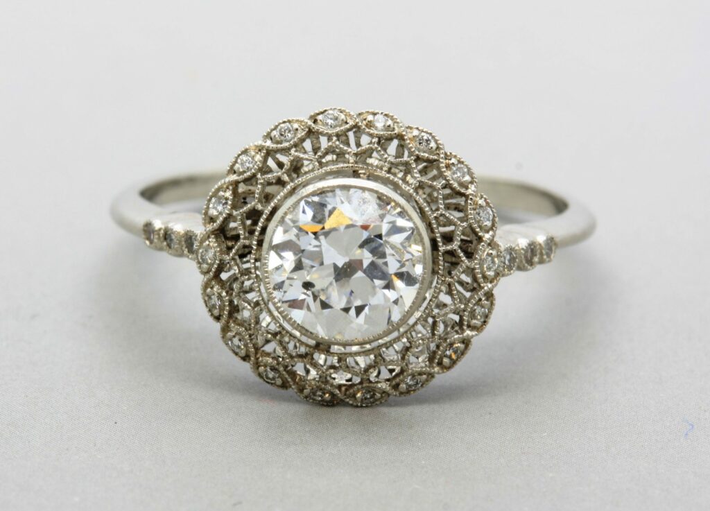 white metal ring with a large round central white stone, and stones wrapping the band