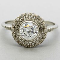 white metal ring with a large round central white stone, and stones wrapping the band